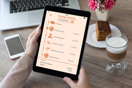 woman hands holding tablet computer with app tracking delivery package on table in cafe