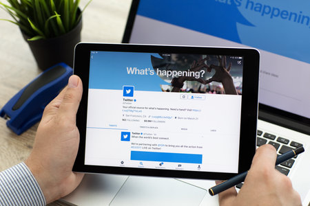 Alushta, Russia - June 7, 2017: Man with MacBook and iPad Pro with social networking service Twitter on the screen. MacBook and iPad Pro was created and developed by the Apple inc.のeditorial素材