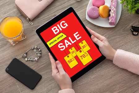 woman hands holding tablet with big sale screen on desk with phoneの写真素材