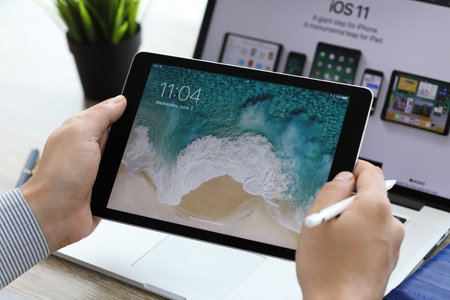 Alushta, Russia - June 7, 2017: Man hand holding iPad Pro with IOS 11 on the screen. iPad and MacBook was created and developed by the Apple inc.のeditorial素材