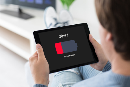 man holding computer tablet with low charged battery on screen in roomの写真素材