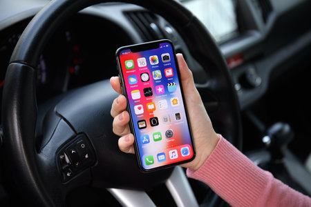 Alushta, Russia - December 16, 2017: Woman hand holding iPhone X with IOS 11 on the screen in the car. iPhone 10 was created and developed by the Apple inc.のeditorial素材