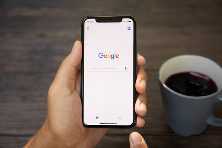 Koh Samui, Thailand - March 22, 2018: Man holding iPhone X with social networking service Google on the screen. iPhone was created and developed by the Apple inc.のeditorial素材