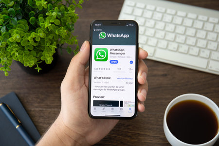 Alushta, Russia - July 30, 2018: Man holding iPhone X with social networking service WhatsApp on the...