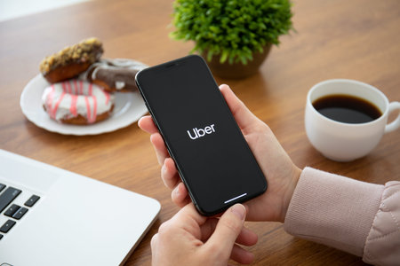 Alushta, Russia - September 28, 2018: Woman hand holding iPhone X with application Taxi Uber on the...