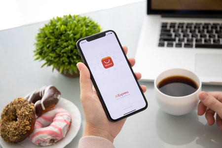 Alushta, Russia - September 28, 2018: Woman holding iPhone X with Internet shopping service Aliexpress on the screen. iPhone 10 was created and developed by the Apple inc.のeditorial素材
