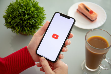 Alushta, Russia - November 6, 2018: Woman holding iPhone X with multinational entertainment company Google provides streaming media and video YouTube on the screen.のeditorial素材