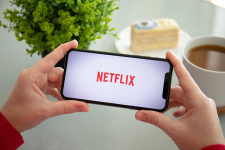 Alushta, Russia - November 6, 2018: Woman holding iPhone X with multinational entertainment company Netflix provides streaming media and video on the screen.のeditorial素材