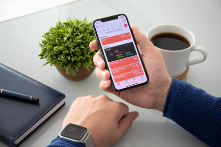 Alushta, Russia - November 3, 2018: Man hand with Apple Watch Series 4 and iPhone X on the table. Apple Watch was created and developed by the Apple inc.のeditorial素材