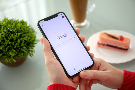 Alushta, Russia - November 6, 2018: Woman holding iPhone X with social networking service Google on the screen. iPhone ten was created and developed by the Apple inc.のeditorial素材