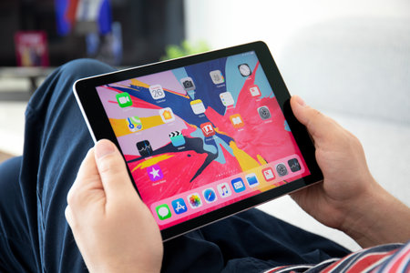 Anapa, Russia - March 26, 2019: Man hand holding iPad Pro with Home page IOS in the screen. iPad was created and developed by the Apple inc.のeditorial素材