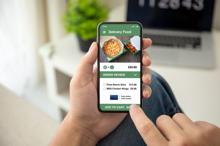 man hands holding phone with app delivery food on the screen in the house in room
