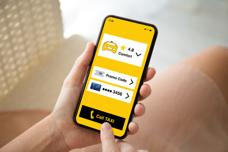 female hands holding phone with app call taxi on the screenの写真素材