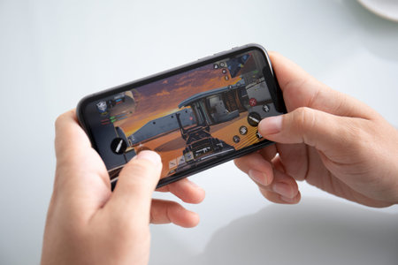 Anapa, Russia - October 5, 2019: Man hand holding iPhone 11 with game Call of Duty Mobile in the...