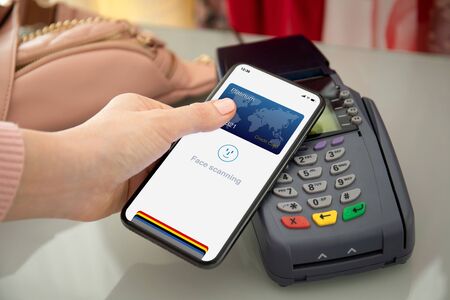 woman hand holding phone with face scanning id and payment purchase on pay pass online terminalの写真素材