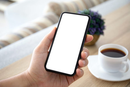 male hands holding phone with isolated screen over a table in the room