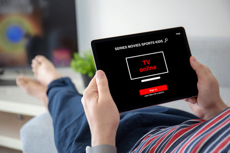 man hands holding computer tablet with app online tv on screen in home room