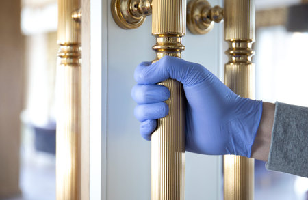 male hand in protective disposable glove from coronavirus virus holds on metal door handle