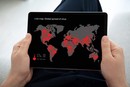 man hands holding computer tablet with live map global spread of virus on the screen in home room