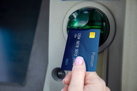 female hand holds credit card and uses it at ATMの写真素材