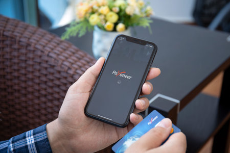 Alanya, Turkey - May 1, 2020: Man hand holding iPhone 11 with app Payoneer on the screen. iPhone was...