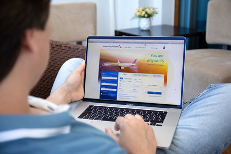 Alanya, Turkey - May 9, 2020: Man hand on Macbook Pro 16 in the table with aircraft ticket sales service American Airlines on the screen.のeditorial素材
