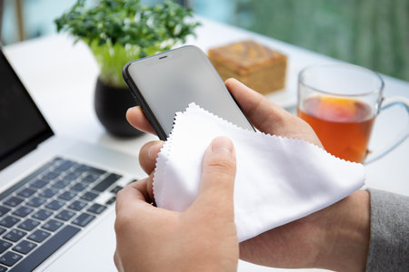 Alanya, Turkey - May 28, 2020: Man hand holding iPhone 11 and rubs the screen with a rag. iPhone 11 was created and developed by the Apple inc.のeditorial素材