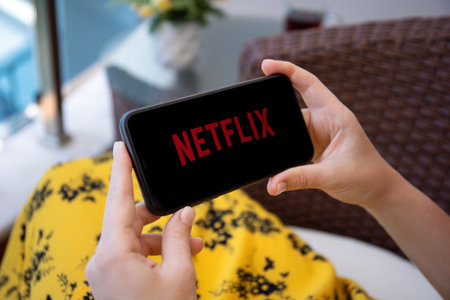 Alanya, Turkey - June 6, 2020: Woman holding iPhone 11 with multinational entertainment company Netflix provides streaming media and video on the screen.のeditorial素材