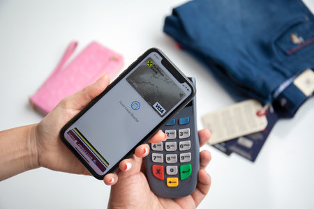 Alanya, Turkey - August 2, 2020: Woman hand holding iPhone 11 with app Raiffeisenbank on the screen and pay pass online POS terminal.のeditorial素材