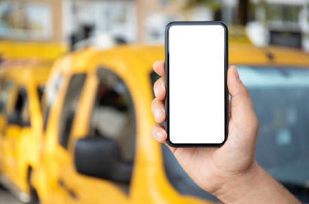 male hand holding phone with isolated screen on background of yellow taxi carsの写真素材