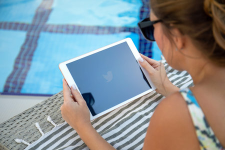Alanya, Turkey - November 2, 2020: Woman at the pool hand holding iPad 7 Gold on the table with...