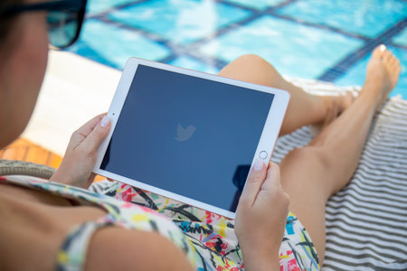 Alanya, Turkey - November 2, 2020: Woman at the pool hand holding iPad 7 Gold with social networking service Twitter on the screen.のeditorial素材