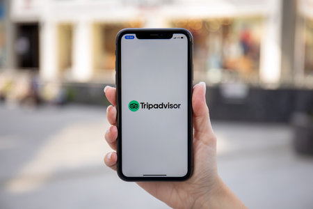 Alanya, Turkey - October 27, 2020: Woman holding iPhone 11 with social networking service Tripadvisor on the screen. iPhone was created and developed by the Apple inc.のeditorial素材