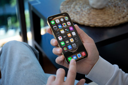 Alanya, Turkey - December 6, 2020: Man hand holding iPhone 12 Pro Max Gold with home screen IOS 14...