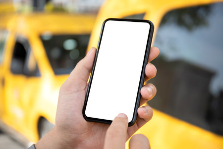 male hand holding phone with isolated screen on background of yellow taxi carsの写真素材