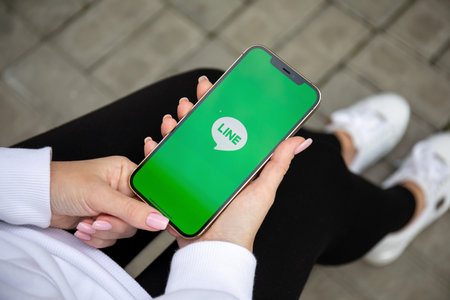 Alanya, Turkey - December 3, 2020: Woman hand holding iPhone 12 Pro Max Gold with social networking service Line on the screen.のeditorial素材