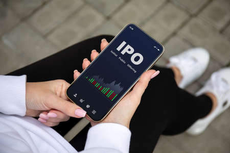 female hands holding the phone with IPO stocks purchase app on the screenの写真素材