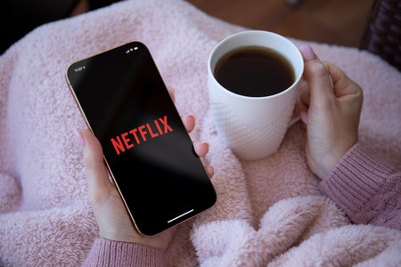 Alanya, Turkey - December 16, 2020: Woman holding iPhone 12 Pro Max Gold with multinational entertainment company Netflix provides streaming media and video on the screen.のeditorial素材