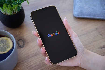 Alanya, Turkey - December 6, 2020: Woman hand with holding Apple iPhone 12 Pro Max Gold with social networking service Google on the screen.のeditorial素材