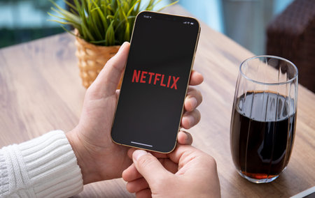 Alanya, Turkey - March 31, 2021: Man holding iPhone 12 Pro Max Gold with multinational entertainment company Netflix provides streaming media and video on the screen.のeditorial素材