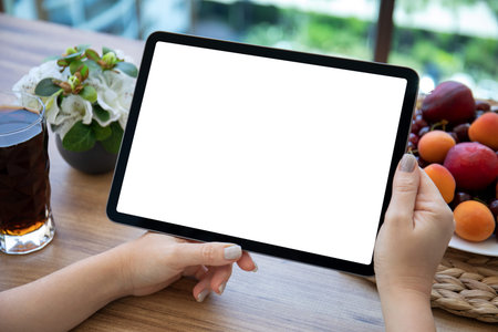 female hands holding computer tablet with isolated screen over table in cafe
