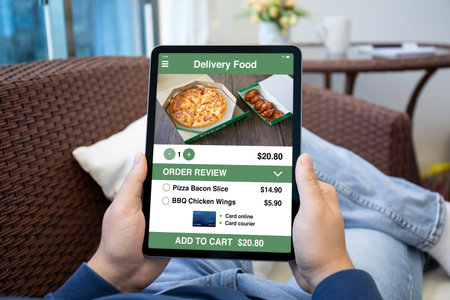 male hands hold computer tablet with food delivery application on screen background room home