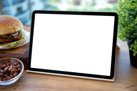 computer tablet with isolated screen on table background burger in cafeの写真素材