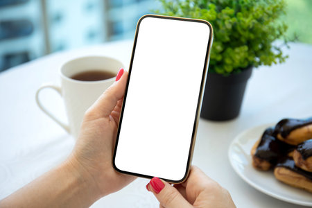female hands holding phone with isolated screen over table in cafe