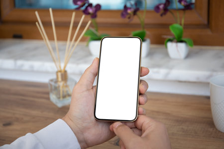 male hands holding phone with isolated screen over table in cafe