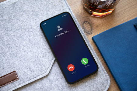 phone with incoming call on screen background of table with blue notepad in officeの写真素材