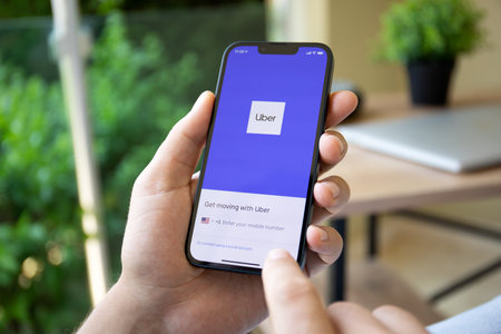Alanya, Turkey - June 9, 2022: Man in the hand Apple iPhone 13 with application Taxi Uber in the screen. iPhone 13 was created and developed by the Apple inc.のeditorial素材