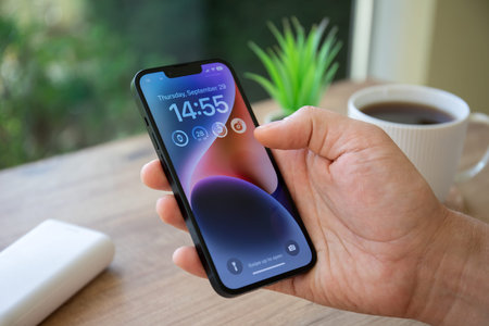 Alanya, Turkey - September 29, 2022: Man hand holding iPhone 14 with home screen IOS 16 on the...