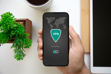 man hand holding phone with app vpn on screen over table in officeの写真素材