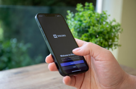 Alanya, Turkey - February 23, 2022: Man hands hold Apple iPhone 13 with calling Discord Video Communications application.のeditorial素材